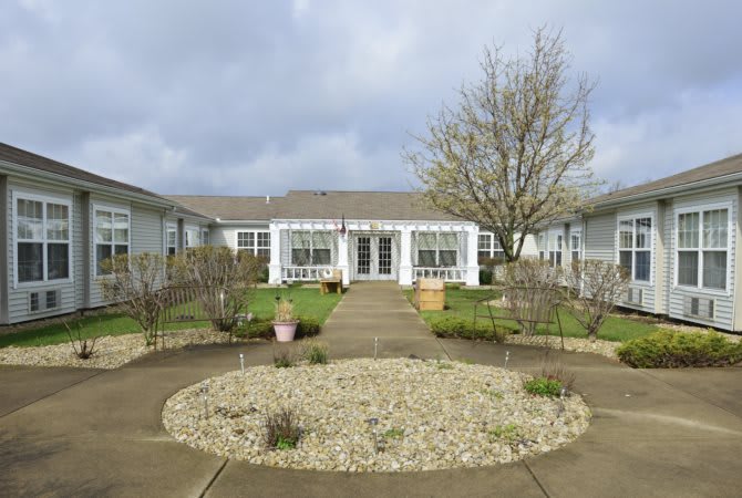 A quaint house with a garden and pathway leading to the entrance on a cloudy day.