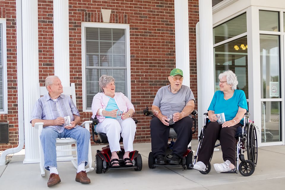 A group of seniors enjoying a conversation while seated outside.