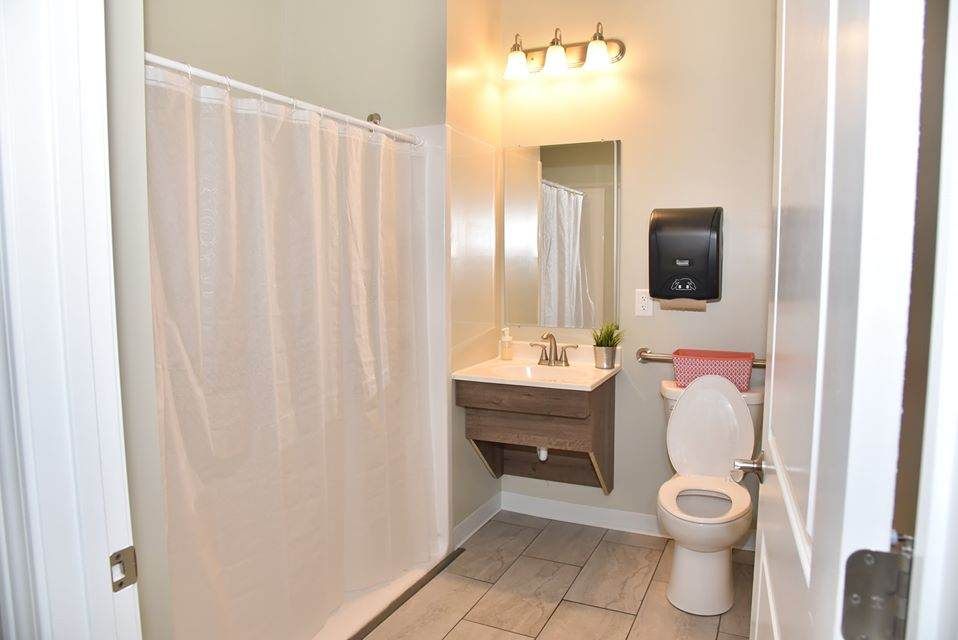 A clean bathroom with a shower curtain, toilet, and sink beneath a mirror.