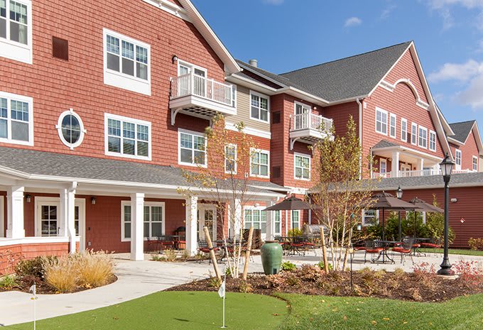 A modern brick residential building with balconies and landscaped surroundings.