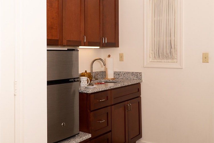 A small kitchen area with wooden cabinets, a granite countertop, and stainless steel appliances.