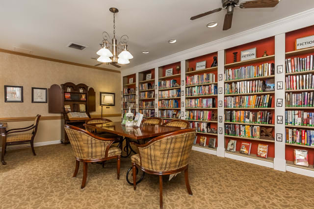 A cozy library room with bookshelves, a reading table, and chairs.