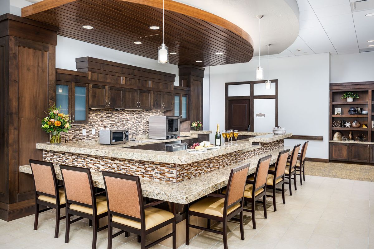 A modern kitchen with a large island counter featuring wood accents and pendant lighting.