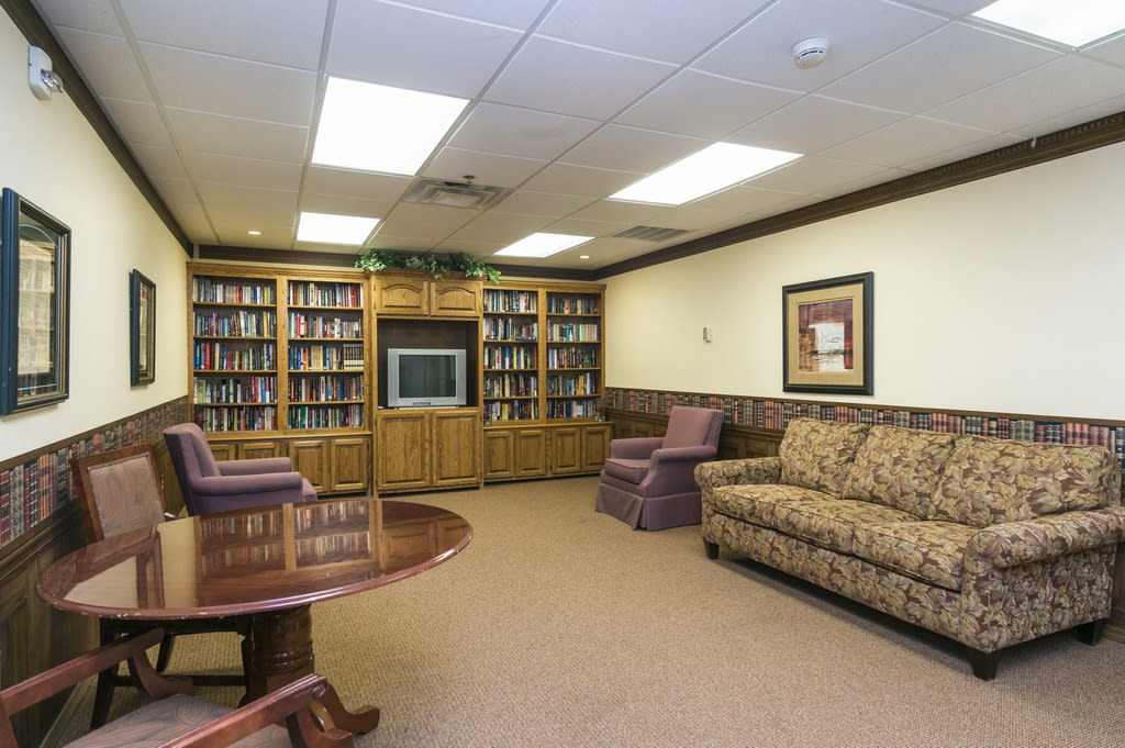 A cozy library room with bookshelves, a TV, and comfortable seating.