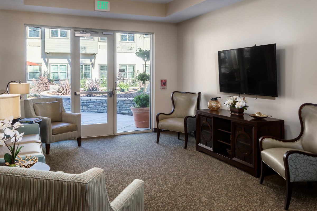 A cozy living room with comfortable seating, a television, and large patio doors leading outside.
