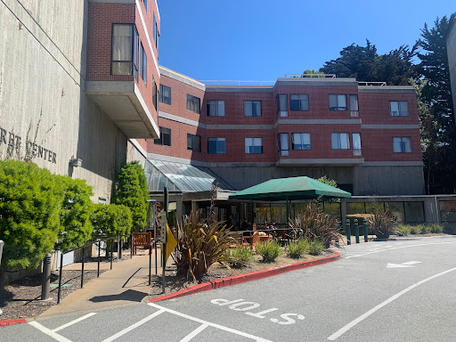 A sunny day at a residential facility featuring outdoor seating and well-maintained landscaping.