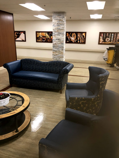 A cozy lounge area featuring a blue sofa and patterned chairs, complemented by a coffee table and artistic photographs on the walls.