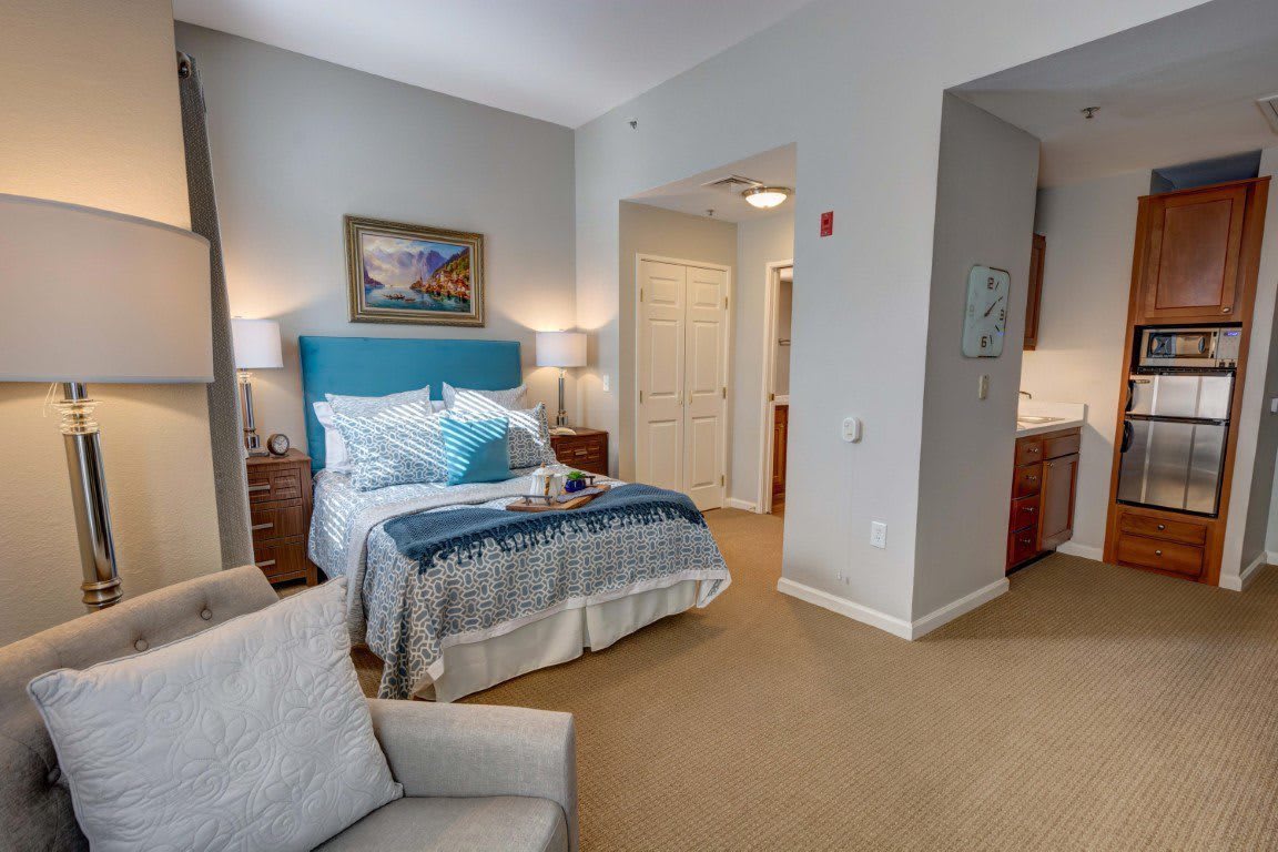 A well-decorated bedroom with a neatly arranged bed, bedside tables, and artwork on the wall.