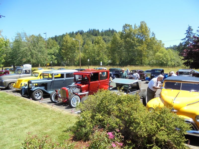 A lineup of classic cars displayed at an outdoor car show on a sunny day.
