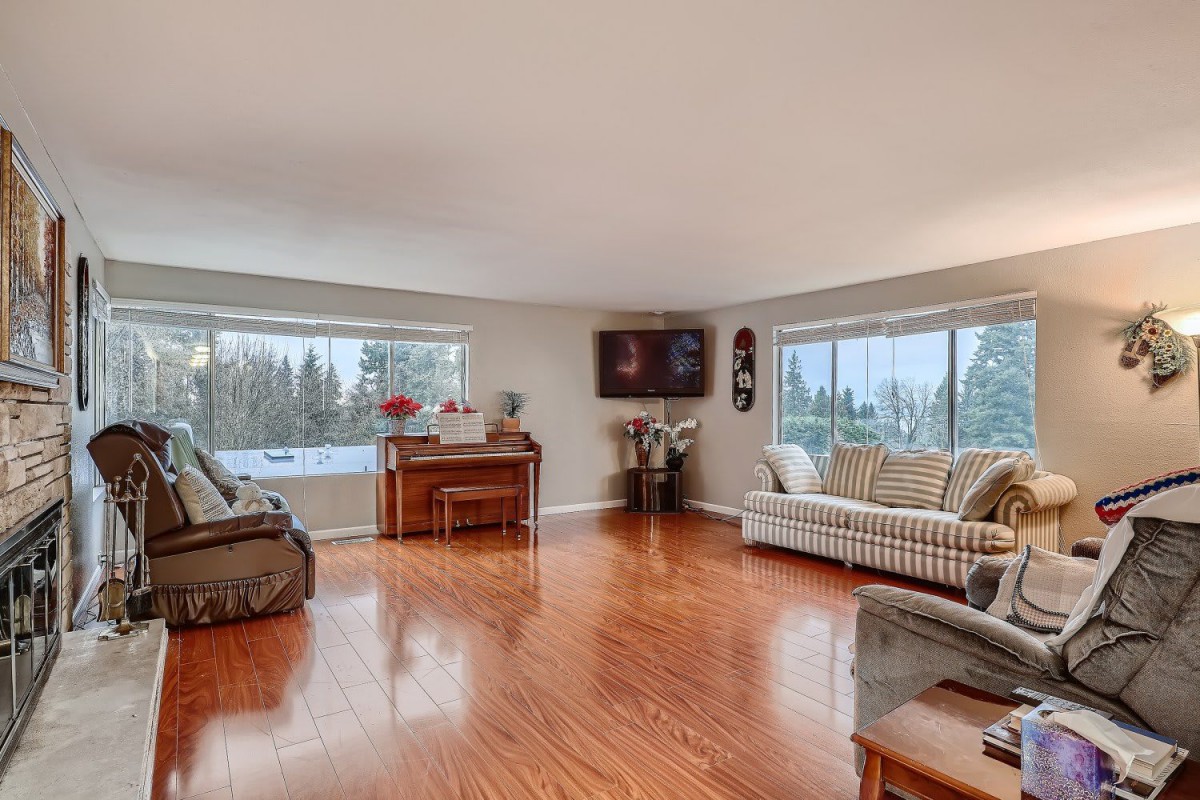 Spacious living room with hardwood flooring and large windows letting in natural light.
