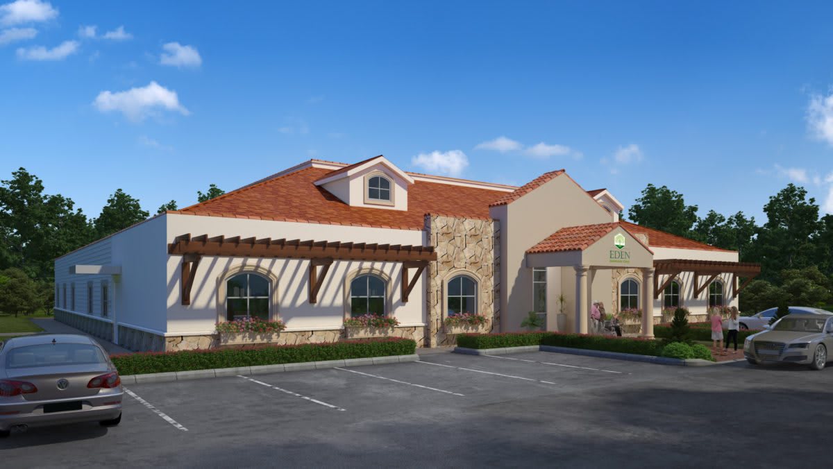 A Mediterranean-style restaurant building with a terracotta roof, stone accents, and an adjacent parking lot under a clear blue sky.