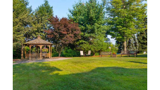 A serene garden space featuring a gazebo surrounded by lush greenery and sunlight.