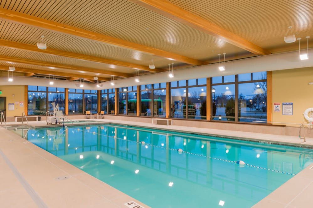 A spacious indoor swimming pool with large windows and bright lighting.