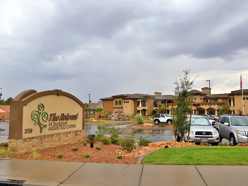 A view of a residential apartment complex with a parking lot and landscaping under an overcast sky.