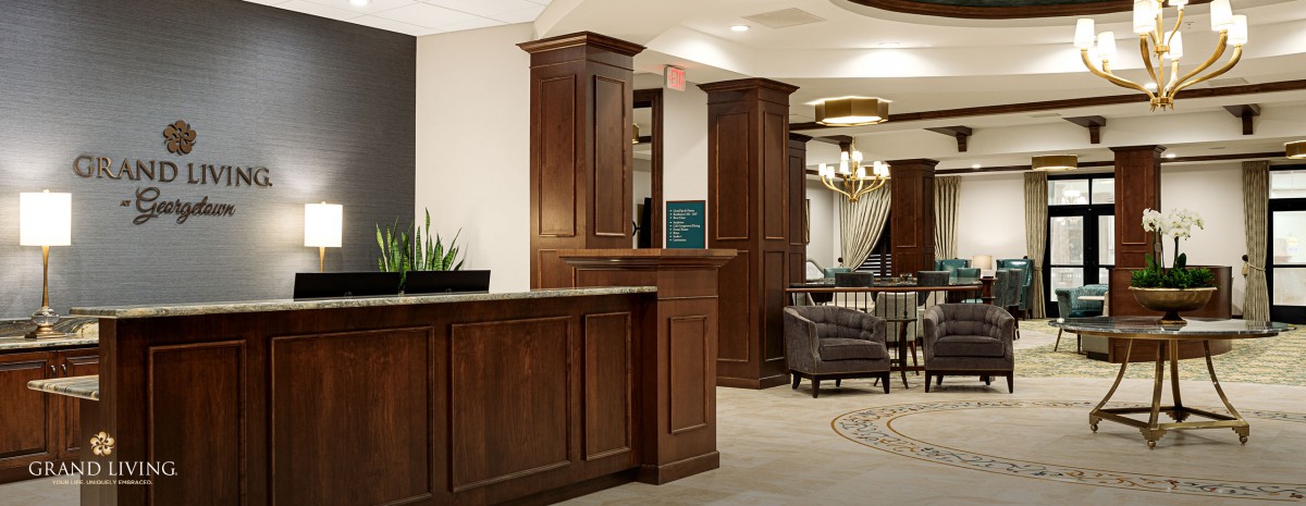 A hotel lobby featuring a wooden reception desk and cozy seating area.