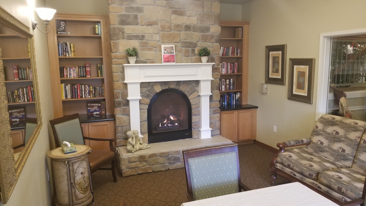 A cozy living room with a stone fireplace and bookshelves filled with books.