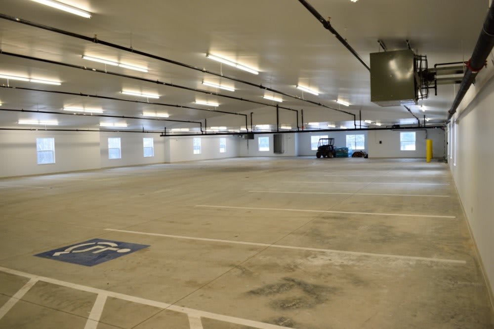 An empty indoor parking garage with bright lighting and a few parked vehicles.