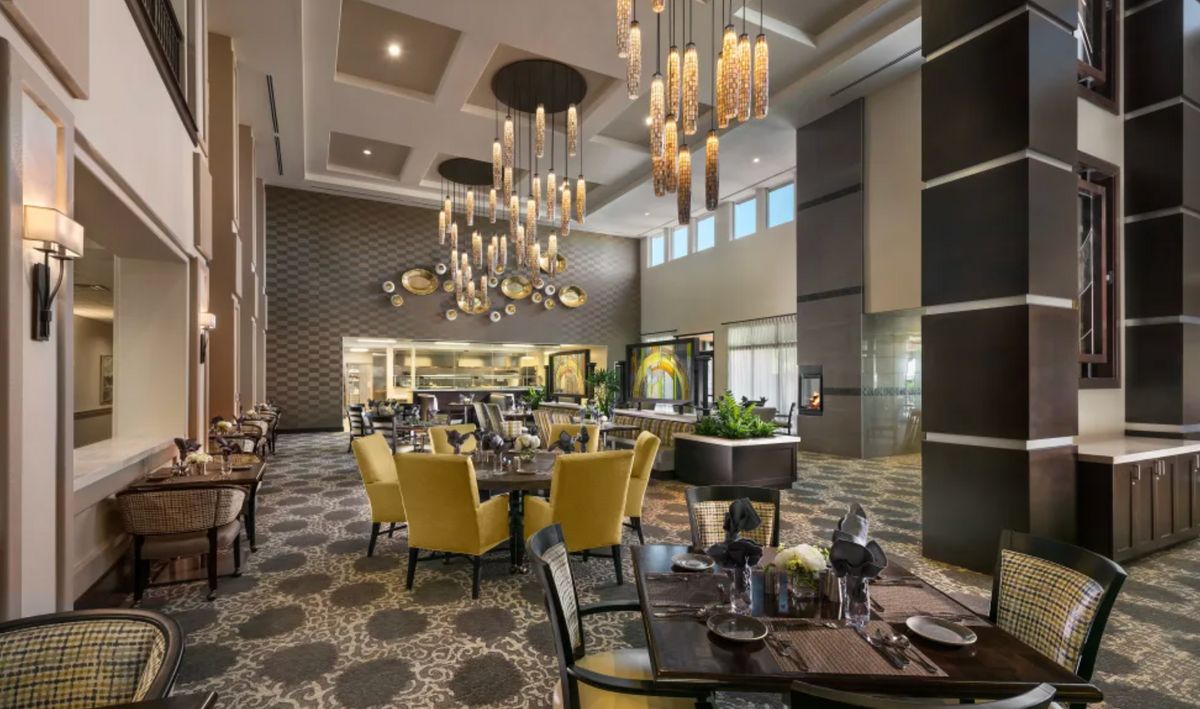 A luxurious restaurant interior featuring elegant chandeliers and stylish yellow chairs.