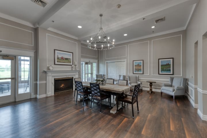 A modern dining room with a chandelier, hardwood flooring, and a fireplace.