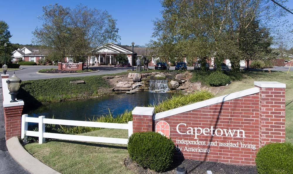 Entrance to Capetown community with a sign, pond, and landscaping.