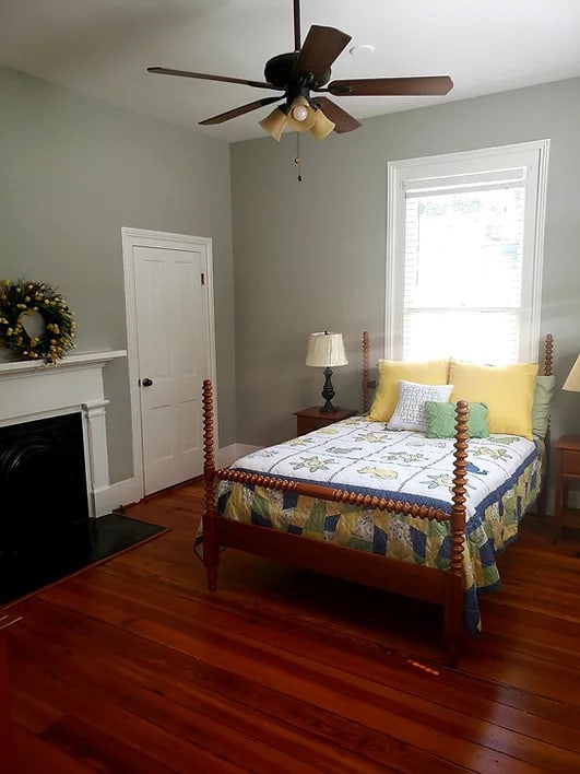 A cozy bedroom with a wooden bed, fireplace, and natural lighting.