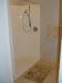 A modern shower area in a bathroom with tiled flooring.