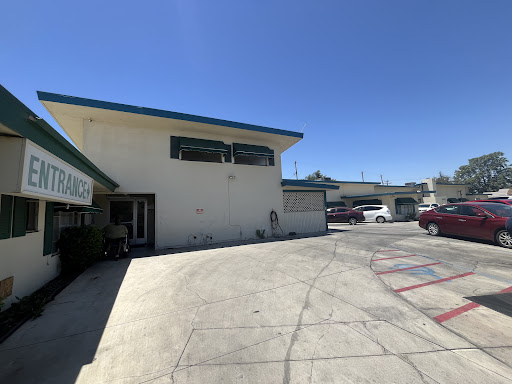 A view of a two-story building with a parking lot under clear blue skies.