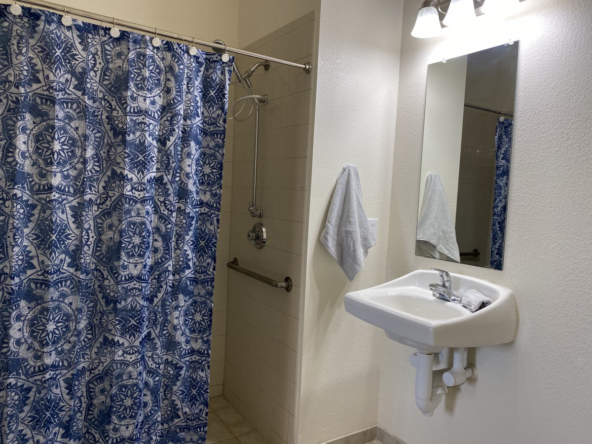 A clean bathroom with a blue patterned shower curtain and a white sink under a mirror.