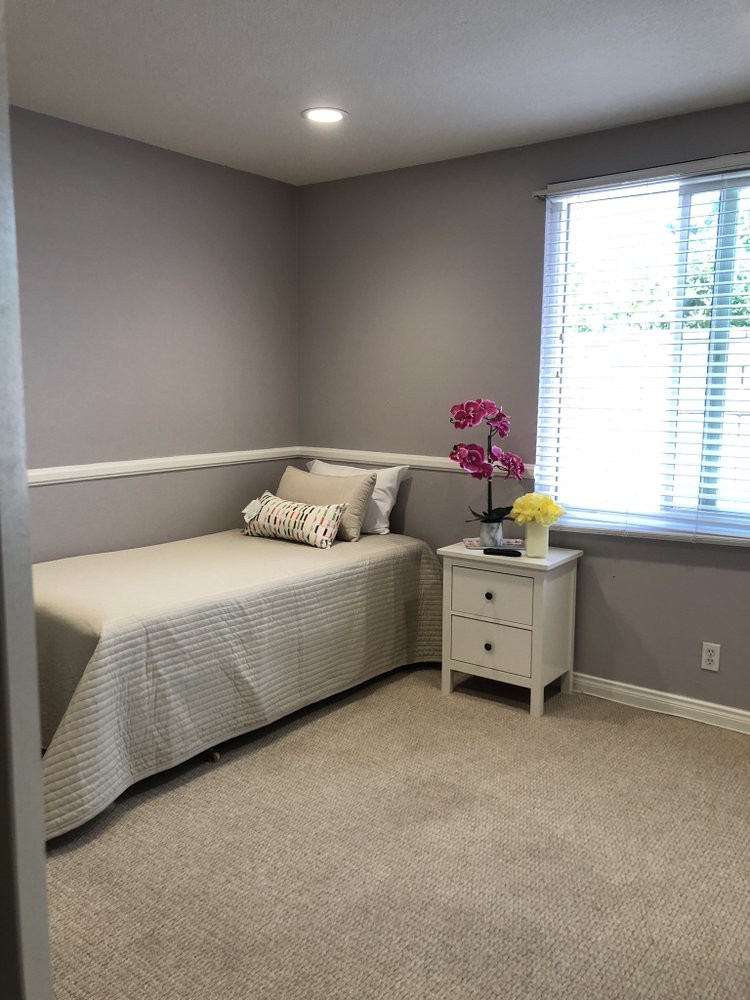 A minimalist bedroom with a single bed, nightstand, and natural light streaming in through the window.