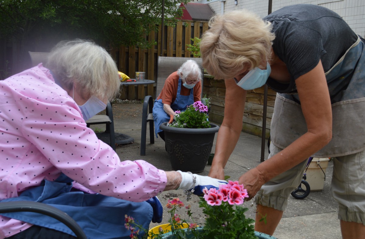 Seniors engaging in a gardening activity while wearing masks.