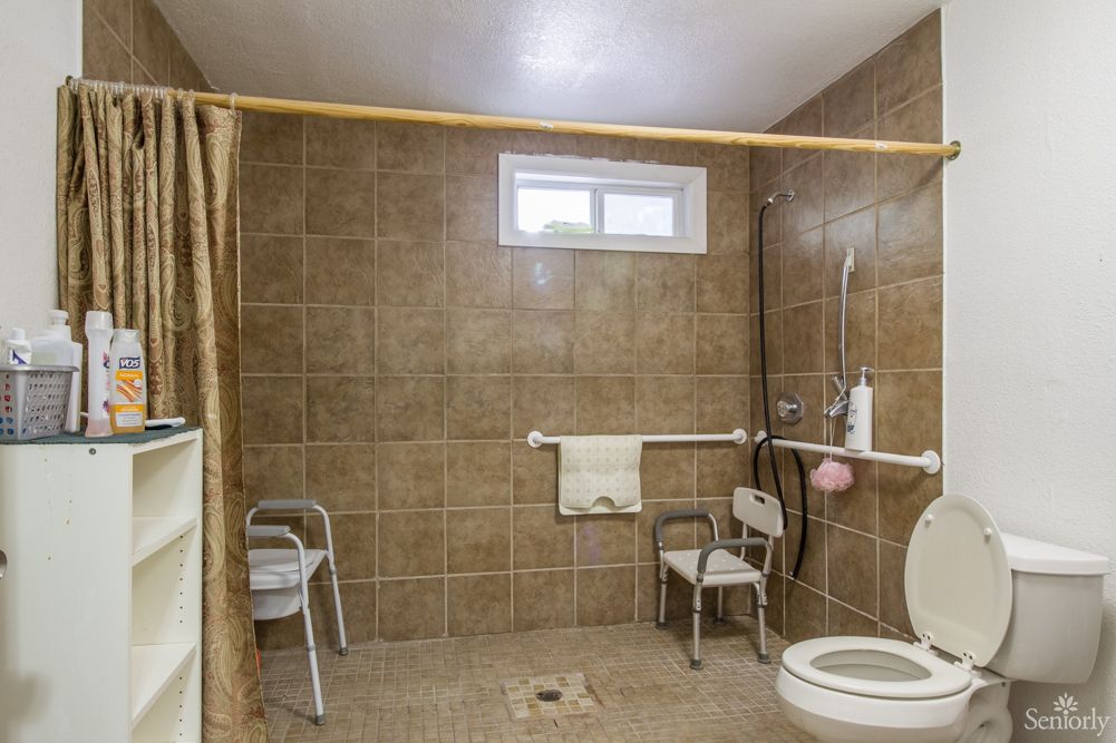 An accessible bathroom equipped with grab bars and a shower chair.