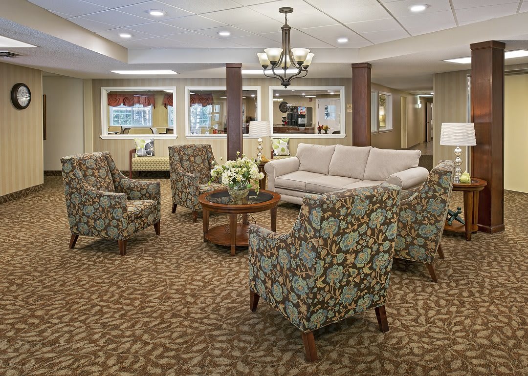 A cozy living room with patterned armchairs, a sofa, and a coffee table set on a carpeted floor.
