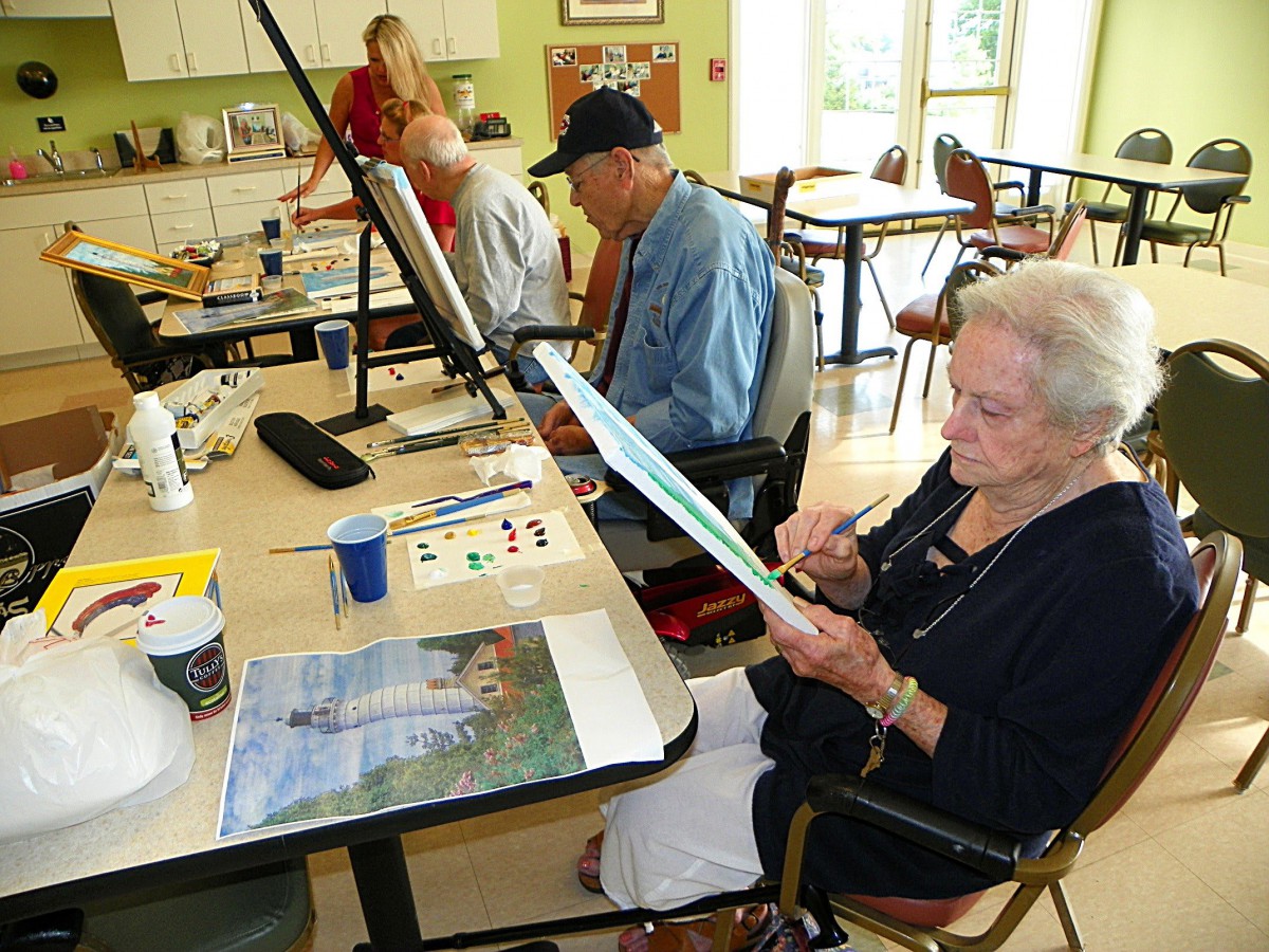 A group of seniors engaged in a painting class, enjoying creative expression together.