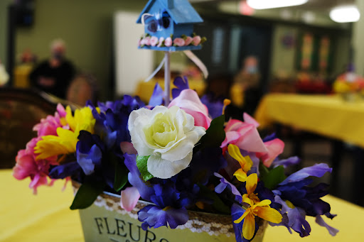 A vibrant floral arrangement featuring a mix of colorful artificial flowers, highlighting a beautiful white rose at the center.