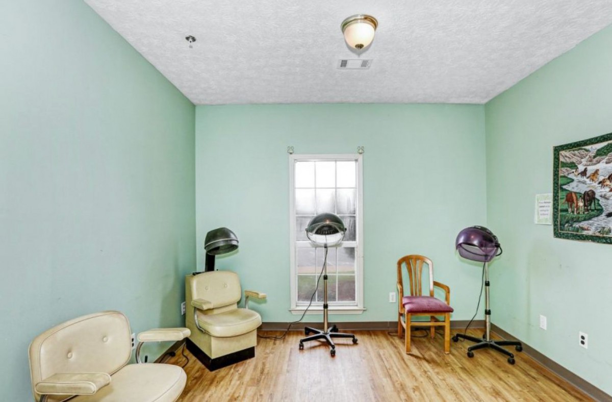 A small hair salon with vintage chairs and hairdryers, featuring mint green walls and a wooden floor.
