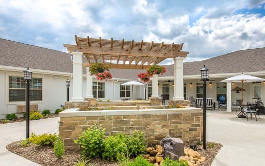 A beautifully designed outdoor space featuring a pergola with hanging flower baskets and elegant landscaping.
