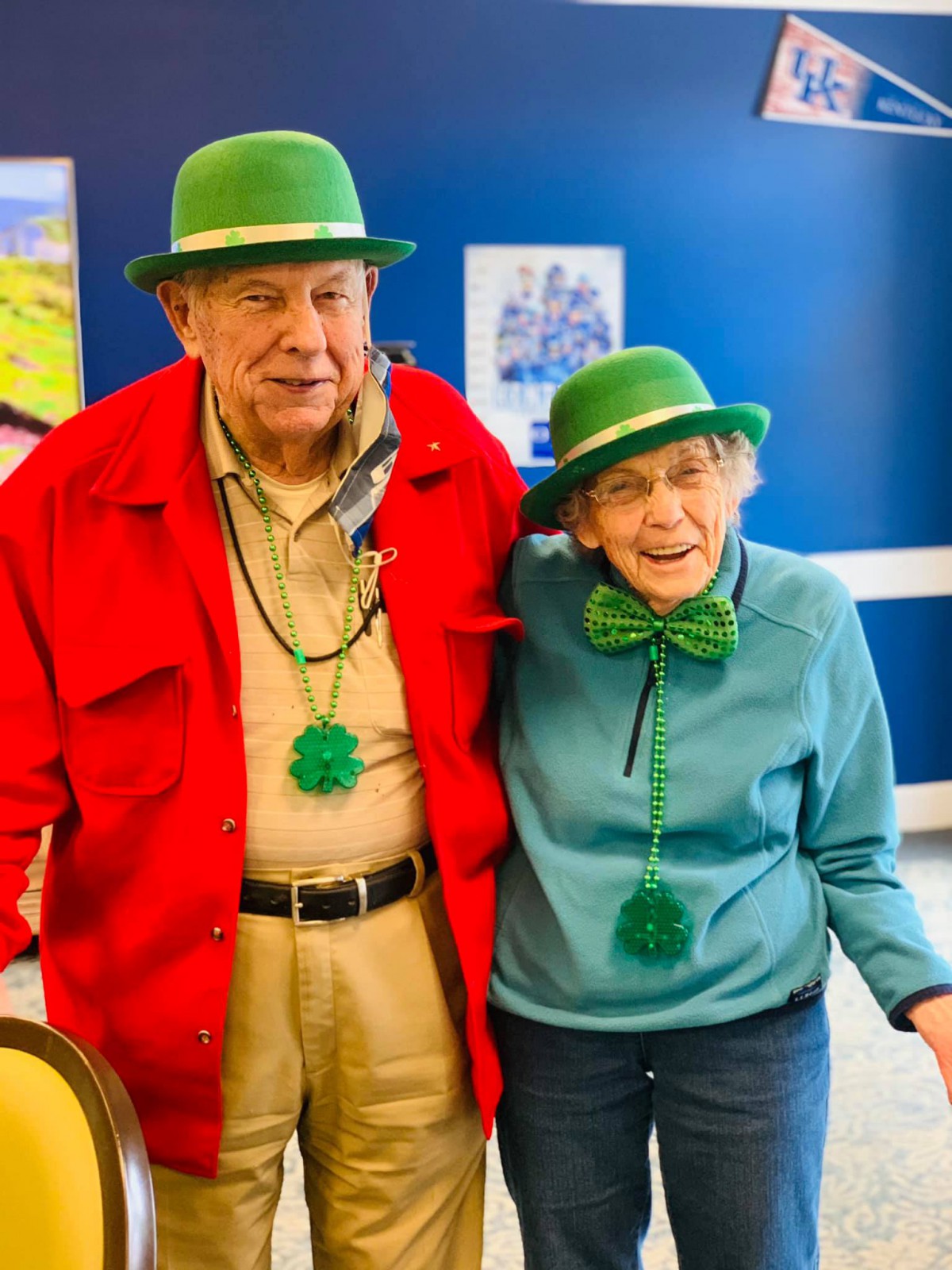 An elderly couple celebrating St. Patrick's Day with green hats and festive attire.