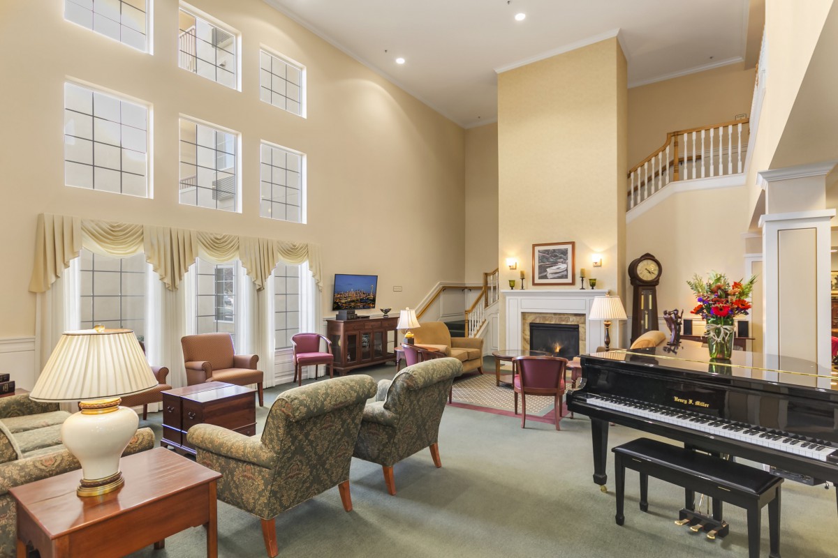 Spacious living room with high ceilings, featuring a cozy seating area and a grand piano.