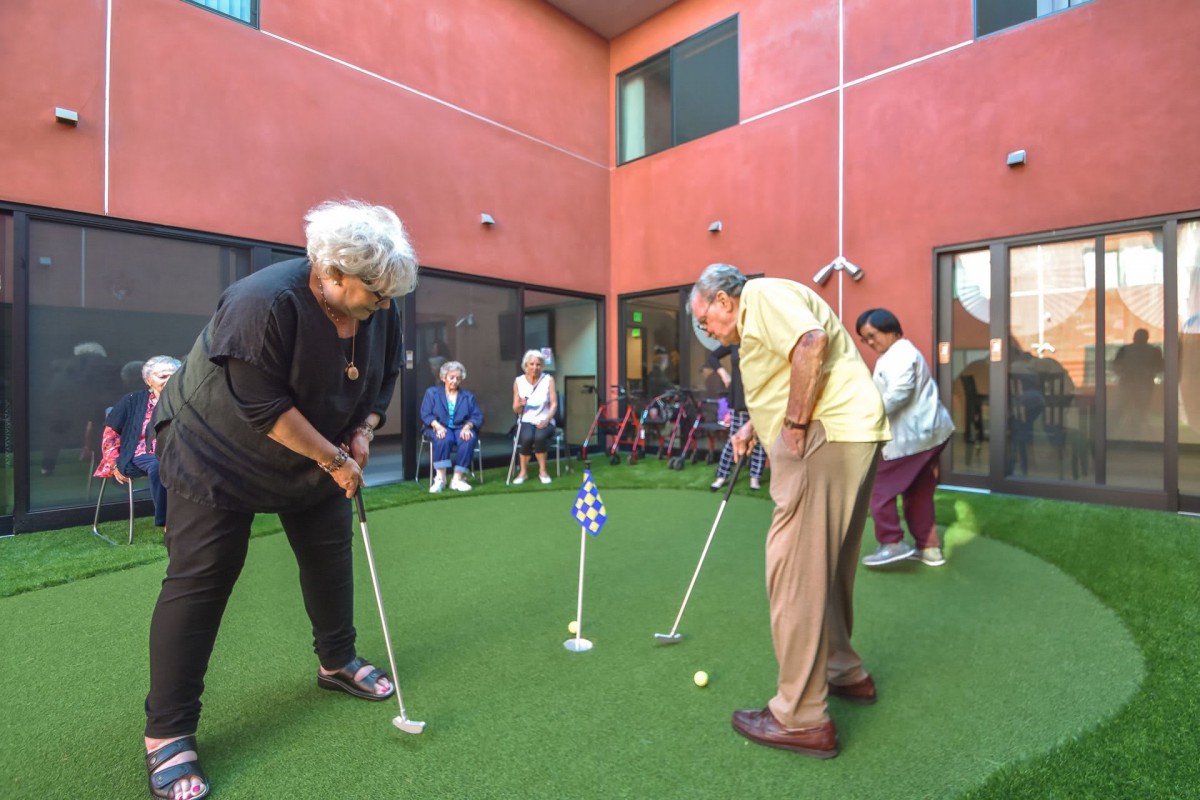 A group of seniors enjoying a game of mini golf on an outdoor putting green.