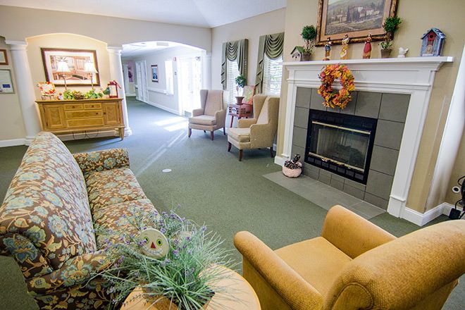 A cozy living room with a fireplace, sofa, and armchairs.