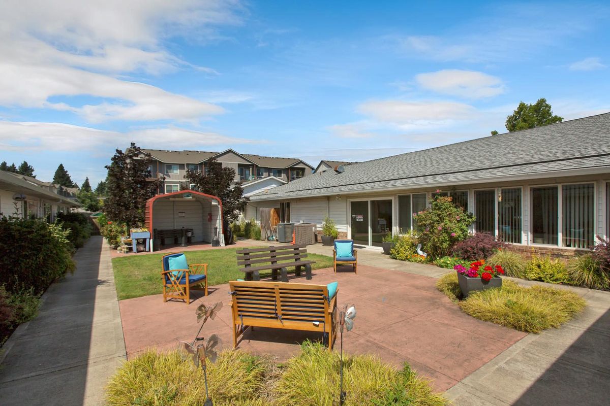 A tranquil outdoor courtyard featuring seating areas and lush landscaping under a clear blue sky.
