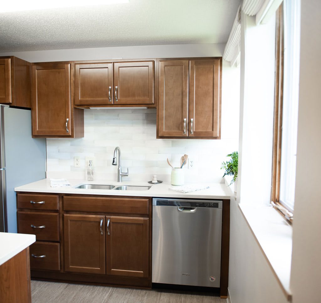 A modern kitchen with wooden cabinets and a stainless steel dishwasher.