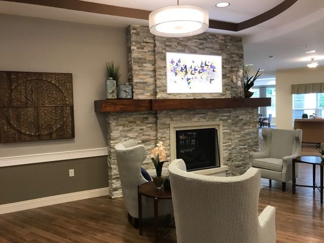 A modern living room with a stone fireplace, elegant armchairs, and warm lighting.