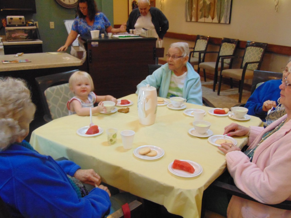 A group of people, including seniors and a child, enjoying a meal together indoors.