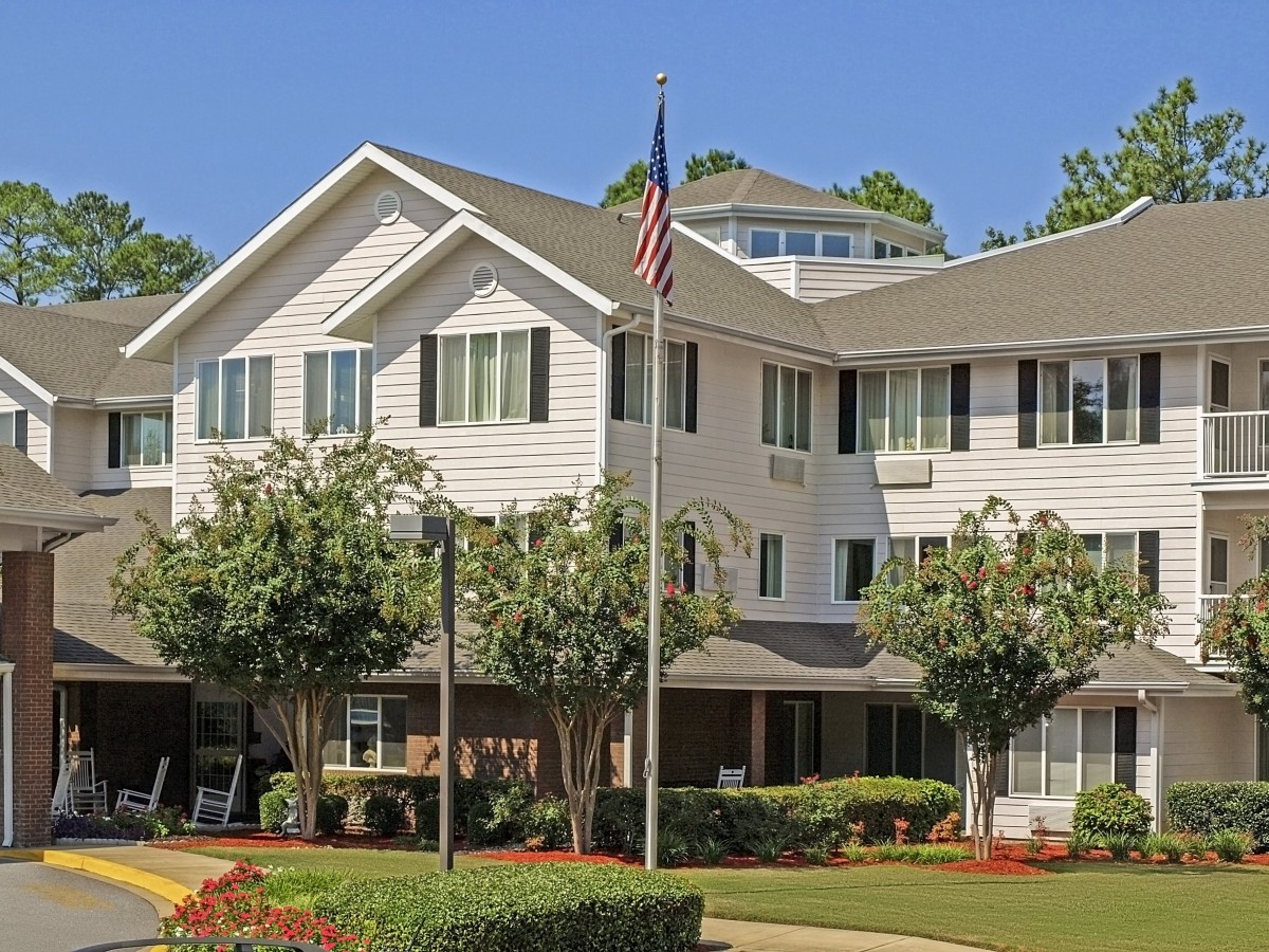 A suburban residential building with well-maintained landscaping and an American flag displayed in front.