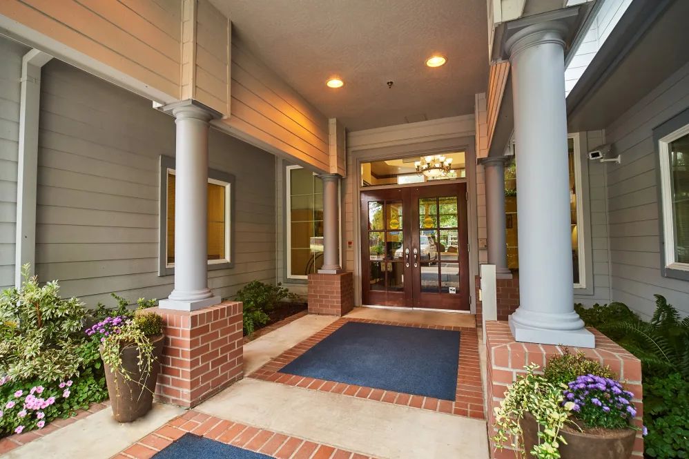 Entrance to a building with columns and decorative plants.