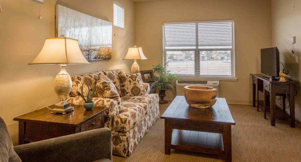 A cozy living room with a patterned sofa, wooden coffee table, and warm lighting.