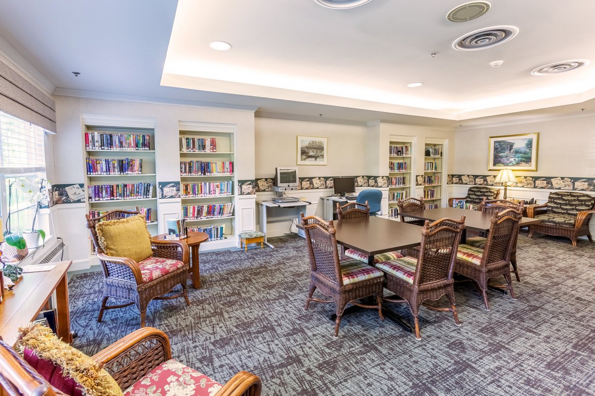 A cozy library room with bookshelves, a table, and chairs.