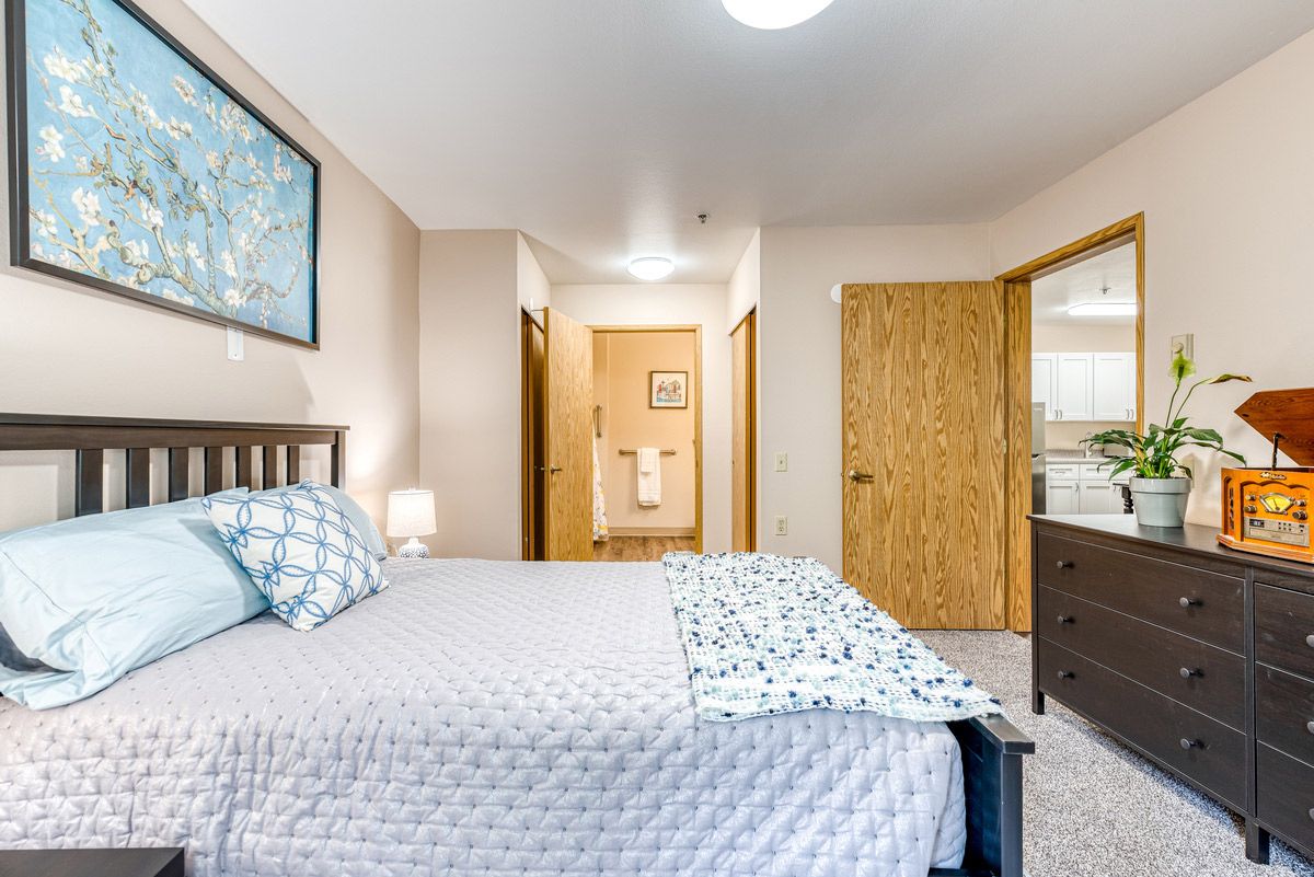 Cozy bedroom with a neatly made bed, nightstand, and soft lighting.