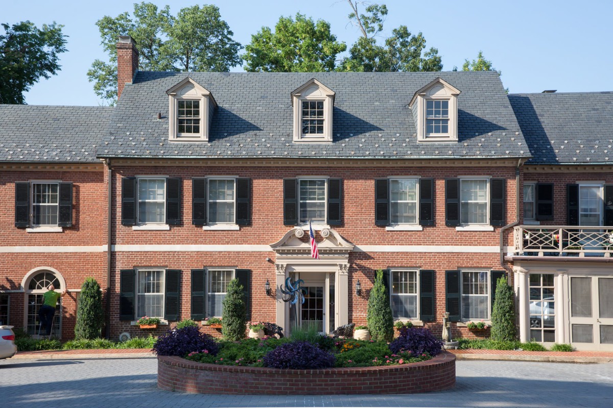 A colonial-style brick house with dormer windows and a well-maintained garden.